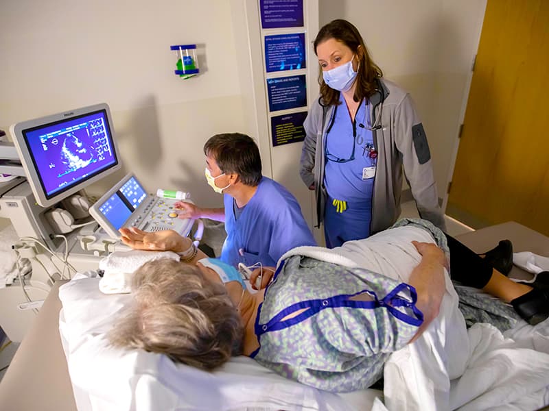 Cardiologist Dr. Kellan Ashley, right, talks with patient Betty Bishop as diagnostic sonographer Karol Black performs an echocardiogram.